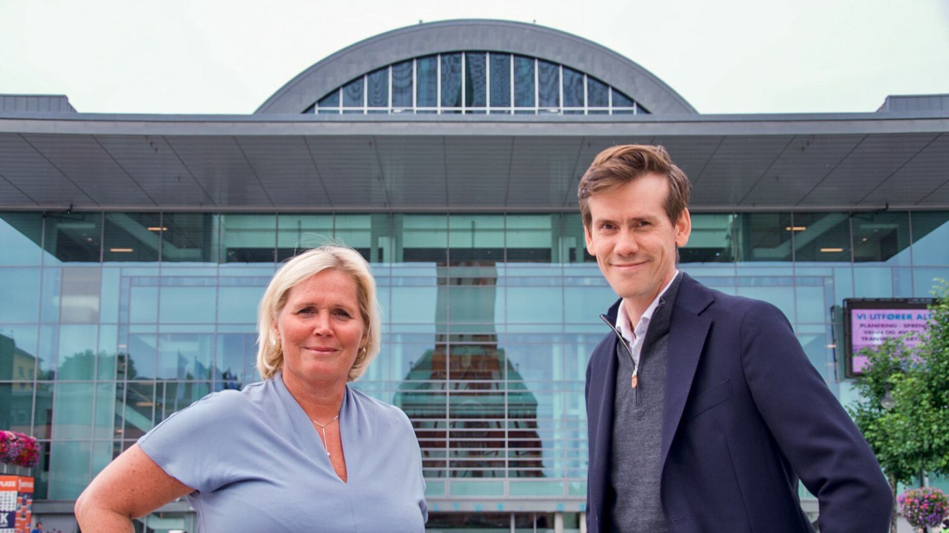 Portrait of Tone Skindlo Taraldsen, Coordinator at Arendalsuka, and Benjamin Golding, CEO of Arendals Fossekompani, standing in front of the cultural centre (kulturhuset).