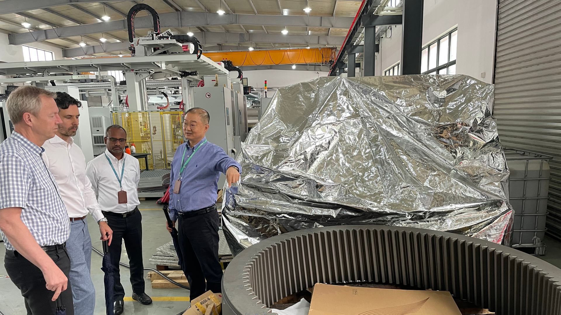 Håkon and Bjørn with colleagues Mahesh Gupta, Maarten Kanters, and Qin Song standing next to industrial machinery and equipment.